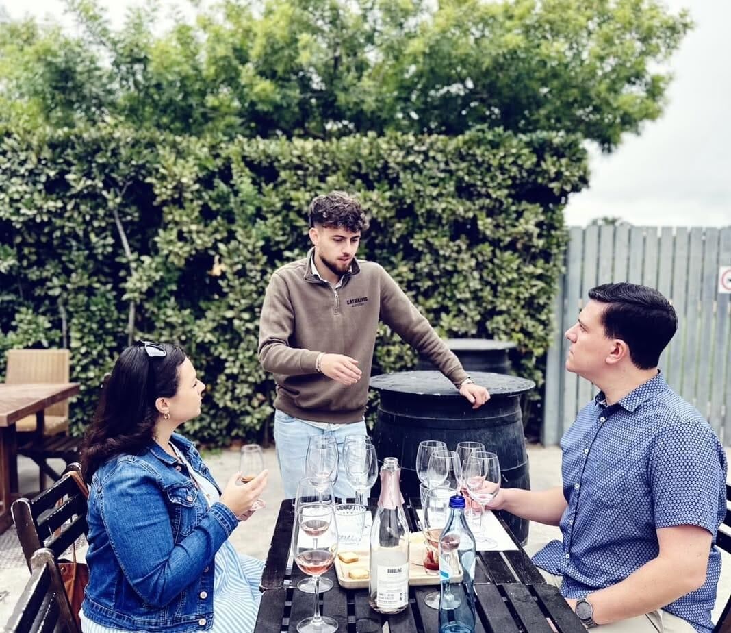 Host guiding a tasting of sparkling and rosé wines at an outdoor table
